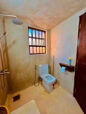 a bathroom with a toilet and a window at Sereno Cabana in Arusha