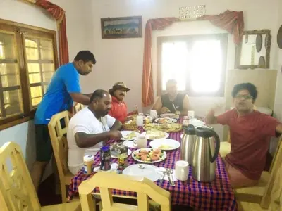 a group of men sitting around a table eating food at Moshi hostel lodge TANZANIA in Moshi
