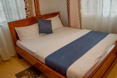 a bed with a wooden headboard and pillows at Silent Inn Apartments in Arusha