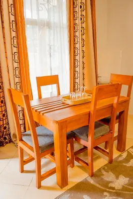 a wooden dining room table with two chairs and a table andermottermott at Silent Inn Apartments in Arusha