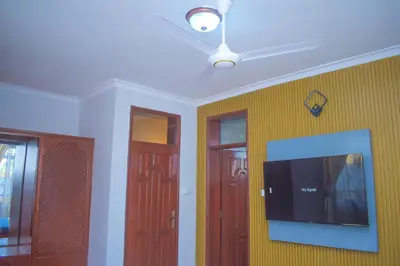a living room with three doors and a tv at Silent Inn Apartments in Arusha