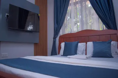 a bed with blue and white pillows and a television at Silent Inn Apartments in Arusha