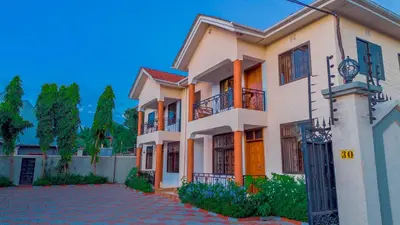 a large house with a driveway in front of it at Silent Inn Apartments in Arusha