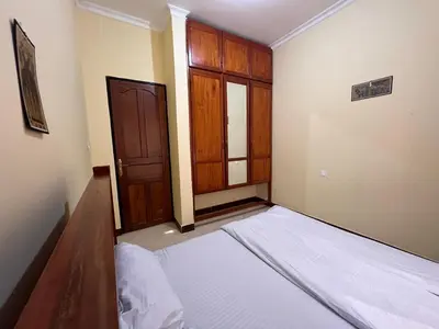 an empty room with a bed and a wooden door at Beego Apartments in Arusha