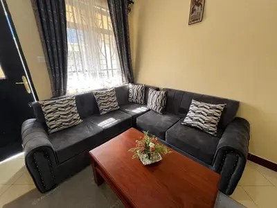 a black leather couch in a living room with a table at Beego Apartments in Arusha