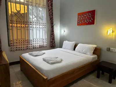 a bedroom with a bed with white sheets and a window at Heim Villa in Kahe