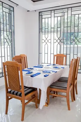 a dining room with a table with chairs and windows at Heim Villa in Kahe