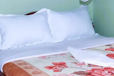 a white bed with two pillows and a blanket at Bamboo Savannah in Arusha