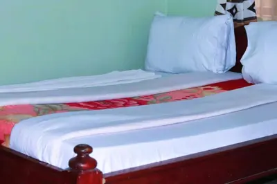 a wooden bed with white sheets and pillows at Bamboo Savannah in Arusha