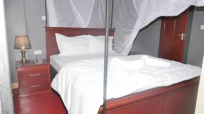 a bed with a wooden frame and white sheets and pillows at Jangwani River View Suits in Mto wa Mbu