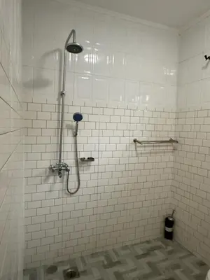 a shower in a bathroom with white tiles at Logic stays 3 bedroom Arusha, Njiro in Arusha