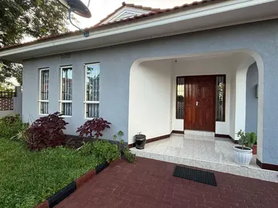 a house with a brown door and a brick patio at Logic stays 3 bedroom Arusha, Njiro in Arusha