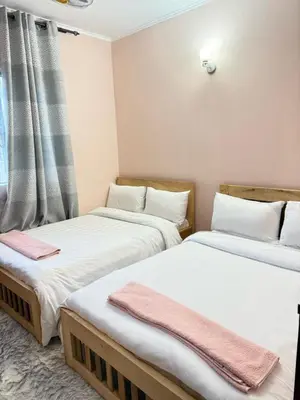 two twin beds in a room with a window at Logic stays 3 bedroom Arusha, Njiro in Arusha