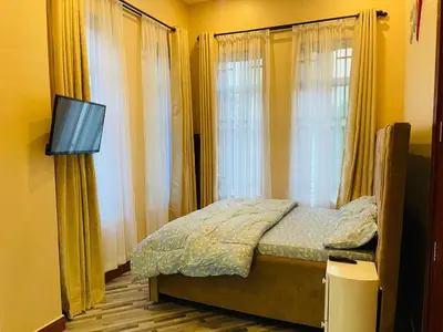 a bedroom with a bed with a tv and windows at Triple s homes in Arusha