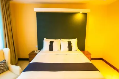 a bedroom with a large bed with yellow walls at Parrot Hotel Arusha in Arusha
