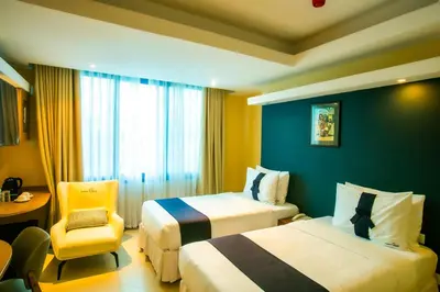 a hotel room with two beds and a chair at Parrot Hotel Arusha in Arusha