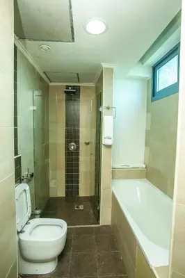 a bathroom with a toilet and a tub and a sink at Parrot Hotel Arusha in Arusha
