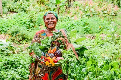 a woman is holding a basket of vegetables at Ngare Sero Mountain Lodge in Usa River