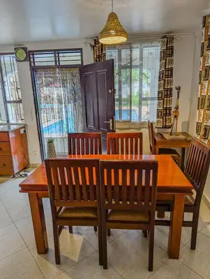 a dining room table with four chairs and a wooden table at SafariVITA Villa in Moshi