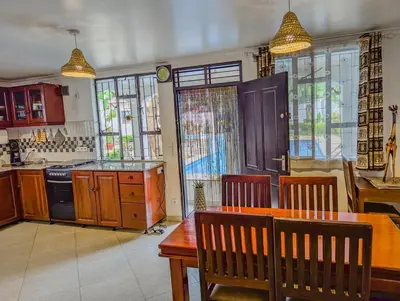 a kitchen with a wooden table and chairs and a kitchen with windows at SafariVITA Villa in Moshi