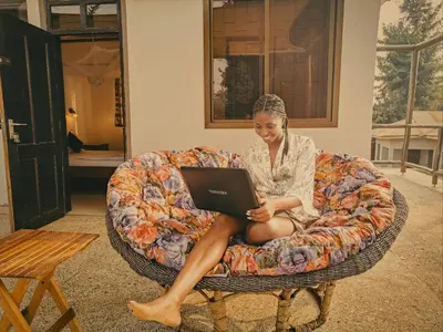 a woman sitting on a couch with a laptop at SafariVITA Villa in Moshi