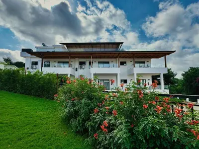 a large white house with flowers in front of it at Moshono Hillside in Arusha