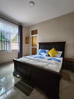 a bedroom with a large bed with blue and yellow pillows at Pembeni River House in Arusha