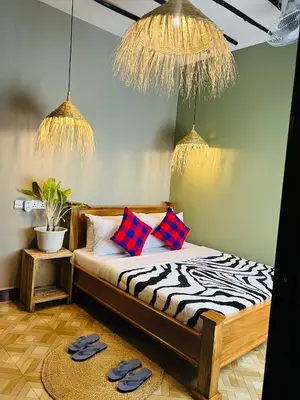a bedroom with a bed with two pillows and a rug at Villa Rosa in Moshi