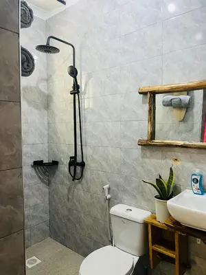 a bathroom with a shower and a toilet and a sink at Villa Rosa in Moshi