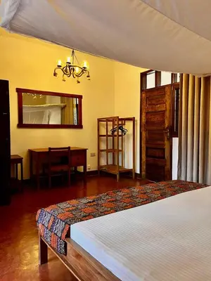 a bedroom with a bed and a table and a mirror at Kilimanjaro Lodge - MCF in Moshi