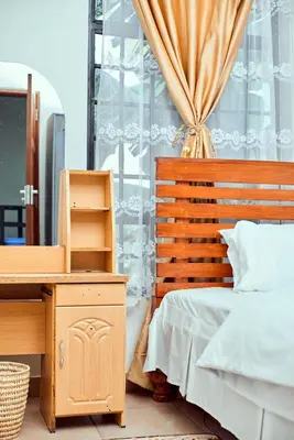 a bedroom with a bed and a desk and a window at Mama Ket Homes Apartment in Arusha