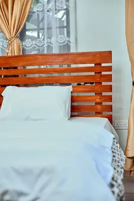 a bedroom with a bed with a wooden headboard at Mama Ket Homes Apartment in Arusha