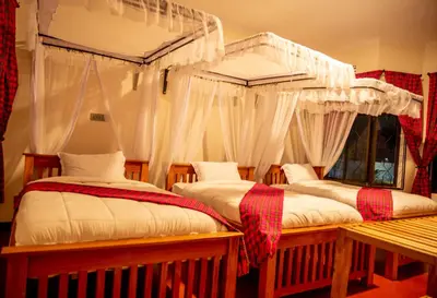 a bedroom with two beds with curtains and a bench at Siafu Serenity Lodge in Mto wa Mbu