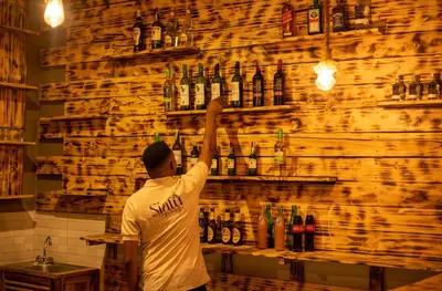 a man standing at a bar with a wall of bottles at Siafu Serenity Lodge in Mto wa Mbu