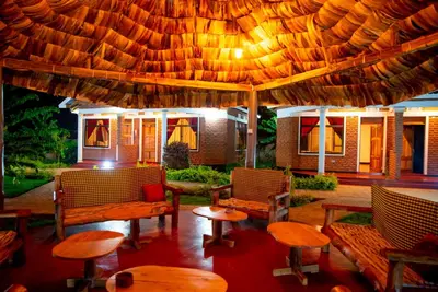a patio with tables and chairs under a large umbrella at Siafu Serenity Lodge in Mto wa Mbu