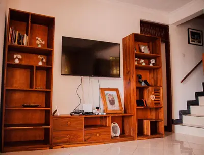 a living room with a large entertainment center with a television at Makinihomestay in Arusha