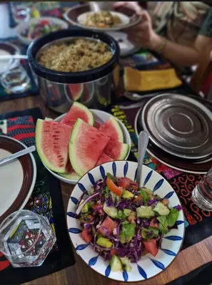 a table with a bowl of salad and watermelon at Makinihomestay in Arusha