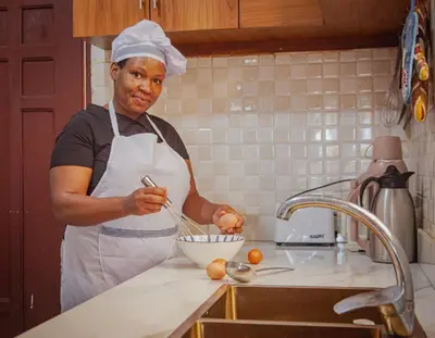 a woman in a kitchen preparing food in a bowl at Makinihomestay in Arusha