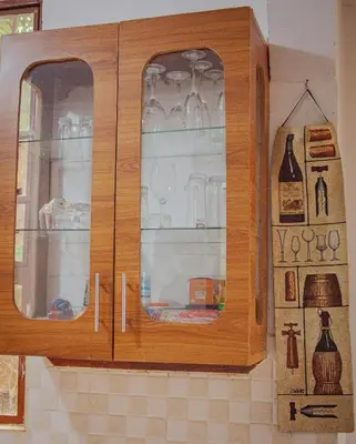 a wooden cabinet with glass doors in a kitchen at Makinihomestay in Arusha