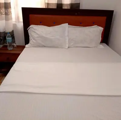a white bed with a wooden headboard and white pillows at Makinihomestay in Arusha