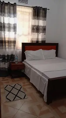 a bedroom with a bed and a window with curtains at Makinihomestay in Arusha