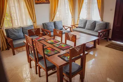 a living room with a wooden table and chairs at Makinihomestay in Arusha