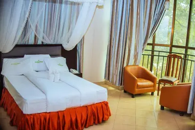 a bedroom with a bed and a chair and a window at Hotel Graceland Arusha in Arusha