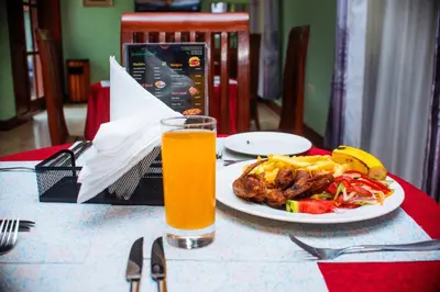 a table with a plate of food and a glass of orange juice at Hotel Graceland Arusha in Arusha