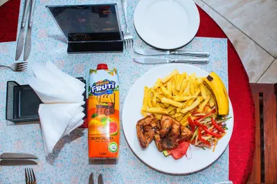a white plate of food with french fries and meat at Hotel Graceland Arusha in Arusha