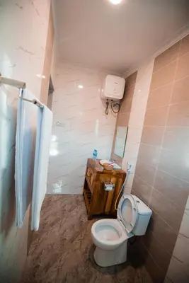 a bathroom with a toilet and a sink and a mirror at Katiti Lodge in Arusha