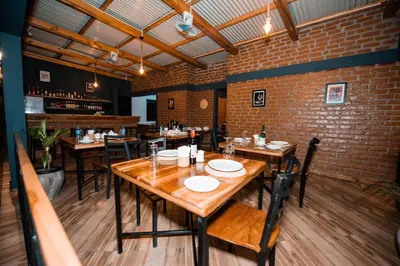 a restaurant with wooden tables and chairs and a brick wall at Katiti Lodge in Arusha