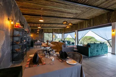 a dining room with a table and chairs and windows at Tarangire Elephant Springs in Engassumet
