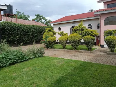 a house with a row of bushes in the yard at Hansat Homestay Residence in Arusha