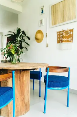 a wooden table with blue chairs and a vase of flowers at Ndani House in Arusha